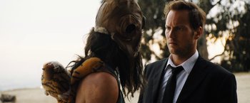 Movie still from “Stretch” (2014), directed by Joe Carnahan – A man in a suit and a man in a mask; Close Up shot, Over the shoulder angle