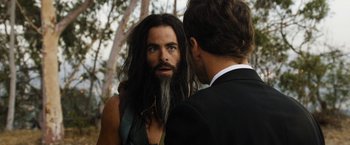 Movie still from “Stretch” (2014), directed by Joe Carnahan – A man with long hair and a beard talking to another man in a suit; Close Up shot, Over the shoulder angle