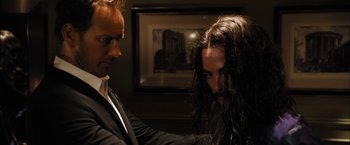 Movie still from “Stretch” (2014), directed by Joe Carnahan – A man in a suit and a man with long black hair; Close Up shot, Over the shoulder angle