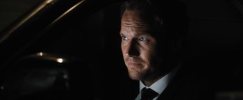 Movie still from “Stretch” (2014), directed by Joe Carnahan – A person wearing a suit and tie; Close Up shot, Over the shoulder angle