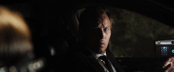 Movie still from “Stretch” (2014), directed by Joe Carnahan – A person wearing a suit in a car; Close Up shot, Over the shoulder angle