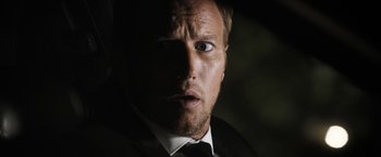Movie still from “Stretch” (2014), directed by Joe Carnahan – A person wearing a suit and tie; Close Up shot, Low angle