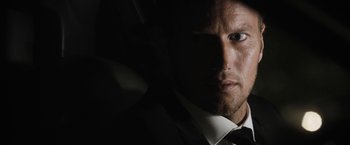 Movie still from “Stretch” (2014), directed by Joe Carnahan – A person wearing a suit and tie; Close Up shot, Low angle