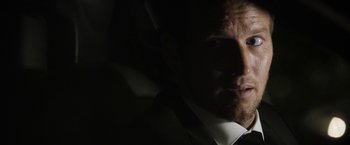 Movie still from “Stretch” (2014), directed by Joe Carnahan – A person wearing a suit and tie; Close Up shot, Over the shoulder angle