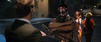 Movie still from “Stretch” (2014), directed by Joe Carnahan – A man with a face paint is holding a guitar; Medium shot, Over the shoulder angle