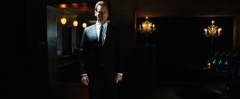 Movie still from “Stretch” (2014), directed by Joe Carnahan – A man in a suit and tie standing in front of a chandelier; Medium shot, Low angle