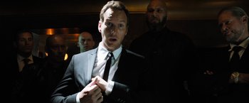 Movie still from “Stretch” (2014), directed by Joe Carnahan – A man in a suit and tie holding a tie; Close Up shot, Low angle