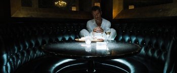 Movie still from “Stretch” (2014), directed by Joe Carnahan – A man sitting at a table with a plate of food; Wide shot, High angle