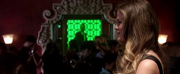 Movie still from “Stretch” (2014), directed by Joe Carnahan – A woman standing in front of a group of people; Medium shot, Over the shoulder angle