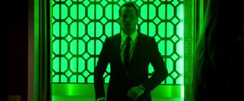Movie still from “Stretch” (2014), directed by Joe Carnahan – A man standing in front of a green wall; Medium shot, Low angle