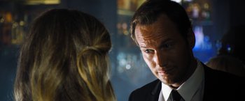 Movie still from “Stretch” (2014), directed by Joe Carnahan – A person wearing a suit and a tie; Close Up shot, Over the shoulder angle