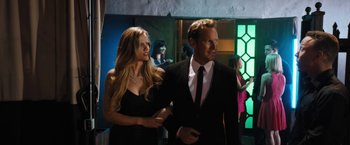 Movie still from “Stretch” (2014), directed by Joe Carnahan – A man and a woman are walking in a room; Medium shot, Over the shoulder angle