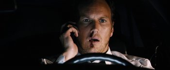 Movie still from “Stretch” (2014), directed by Joe Carnahan – A man in a suit talking on a cell phone while sitting in a car; Close Up shot, Over the shoulder angle