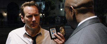 Movie still from “Stretch” (2014), directed by Joe Carnahan – A man holding a photo of himself in front of another man; Close Up shot, Over the shoulder angle