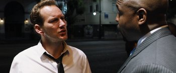 Movie still from “Stretch” (2014), directed by Joe Carnahan – A man wearing a white dress shirt and a black tie talking to another man wearing a white dress shirt and a black tie; Close Up shot, Over the shoulder angle