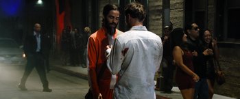 Movie still from “Stretch” (2014), directed by Joe Carnahan – A man in an orange and white suit is talking to another man in an orange and white suit; Medium shot, Over the shoulder angle