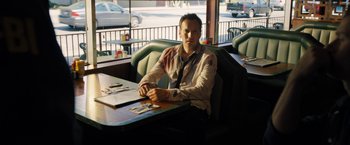 Movie still from “Stretch” (2014), directed by Joe Carnahan – A man sitting at a table in front of papers; Medium shot, High angle