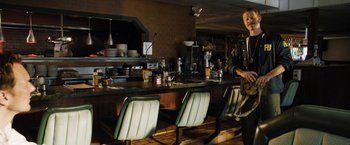 Movie still from “Stretch” (2014), directed by Joe Carnahan – A man standing in front of a counter in a kitchen; Medium shot, Over the shoulder angle