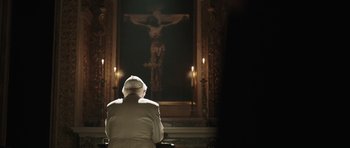 Movie still from “Suburra” (2015), directed by Stefano Sollima – A man in a priest's outfit looking at a crucifixion; Wide shot, Low angle