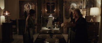 Movie still from “Suburra” (2015), directed by Stefano Sollima – A man kneeling down in front of a painting; Wide shot, High angle