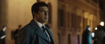 Movie still from “Suburra” (2015), directed by Stefano Sollima – A person wearing a suit and tie; Close Up shot, Low angle