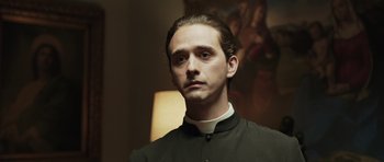 Movie still from “Suburra” (2015), directed by Stefano Sollima – A man in a priest's outfit is looking at the camera; Close Up shot, Low angle
