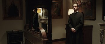 Movie still from “Suburra” (2015), directed by Stefano Sollima – A man standing in front of a mirror in front of a fireplace; Medium shot, Low angle