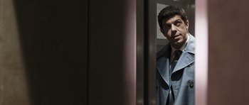 Movie still from “Suburra” (2015), directed by Stefano Sollima – A man standing in front of a door looking at the camera; Medium shot, Low angle