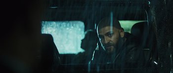 Movie still from “Suburra” (2015), directed by Stefano Sollima – A man sitting in the passenger seat of a car in the rain; Close Up shot, Over the shoulder angle