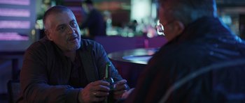 Movie still from “Suburra” (2015), directed by Stefano Sollima – A man and a woman sitting at a table with a bottle of beer; Close Up shot, Over the shoulder angle