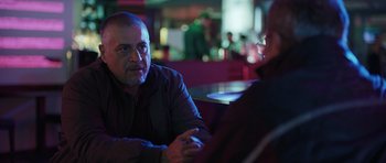 Movie still from “Suburra” (2015), directed by Stefano Sollima – A man sitting at a table in front of another man; Close Up shot, Over the shoulder angle