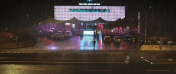 Movie still from “Suburra” (2015), directed by Stefano Sollima – A person walking on a sidewalk in front of a restaurant; Extreme Wide shot, Low angle