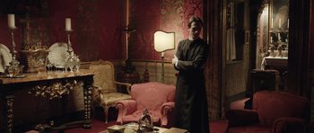 Movie still from “Suburra” (2015), directed by Stefano Sollima – A man standing in front of a lamp in a living room; Medium shot, High angle