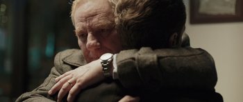 Movie still from “Suburra” (2015), directed by Stefano Sollima – A man hugging another man with a watch; Close Up shot, Over the shoulder angle