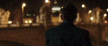 Movie still from “Suburra” (2015), directed by Stefano Sollima – A man in a suit looking out a window at night; Medium shot, Over the shoulder angle