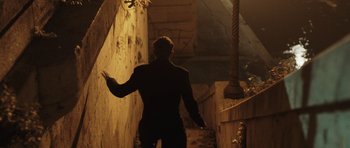 Movie still from “Suburra” (2015), directed by Stefano Sollima – A man standing in a dark alley with his arms outstretched; Wide shot, High angle