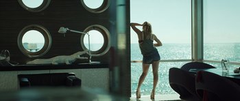 Movie still from “Suburra” (2015), directed by Stefano Sollima – A woman standing on a deck looking out a window; Wide shot, Over the shoulder angle