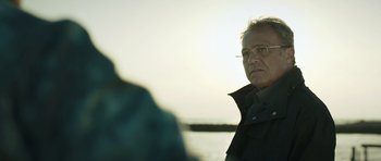 Movie still from “Suburra” (2015), directed by Stefano Sollima – An older man wearing glasses and a black jacket; Close Up shot, Low angle