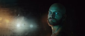 Movie still from “Suburra” (2015), directed by Stefano Sollima – A man with a bald head and a beard; Close Up shot, Low angle