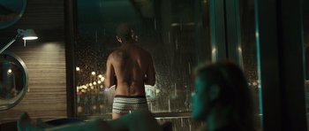 Movie still from “Suburra” (2015), directed by Stefano Sollima – A man with no shirt standing in front of a window; Medium shot, Over the shoulder angle