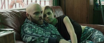 Movie still from “Suburra” (2015), directed by Stefano Sollima – A man and a woman sitting next to each other on a couch; Close Up shot, Over the shoulder angle