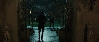 Movie still from “Suburra” (2015), directed by Stefano Sollima – Two people are walking down a path in the dark; Wide shot, Over the shoulder angle