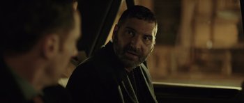 Movie still from “Suburra” (2015), directed by Stefano Sollima – A person with a beard in a car; Close Up shot, Over the shoulder angle