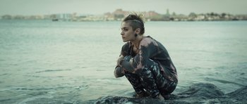 Movie still from “Suburra” (2015), directed by Stefano Sollima – A woman sitting on a rock in the water; Medium shot, High angle