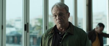 Movie still from “Suburra” (2015), directed by Stefano Sollima – An older man wearing glasses and a green jacket; Close Up shot, Low angle