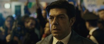 Movie still from “Suburra” (2015), directed by Stefano Sollima – A person wearing a suit and tie; Close Up shot, Low angle