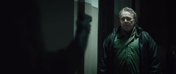 Movie still from “Suburra” (2015), directed by Stefano Sollima – A man standing in front of a wall holding a gun; Medium shot, Over the shoulder angle