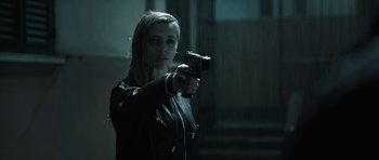 Movie still from “Suburra” (2015), directed by Stefano Sollima – A woman holding a gun while standing in a dark room; Medium shot, Low angle