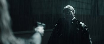 Movie still from “Suburra” (2015), directed by Stefano Sollima – A man in a black jacket is standing in the rain; Medium shot, Over the shoulder angle