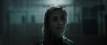Movie still from “Suburra” (2015), directed by Stefano Sollima – A woman standing in front of a glass window; Close Up shot, Low angle